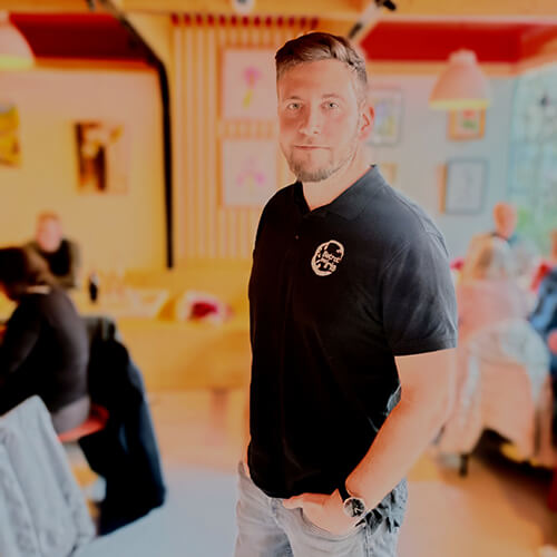 Cyril de l'équipe du Bistrot les Iris posant à l'intérieur parmi les clients